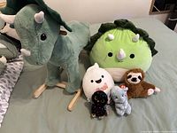 All items arranged on bed including rocking dinosaur and six plush toys