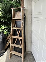Full view of closed wooden ladder leaning against wall