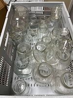 Crate containing mixed clear glass jars