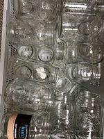 Top-down view of numerous clear glass jars filling a crate