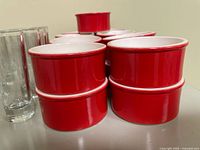 Red ceramic ramekins stacked with shot glass edge visible