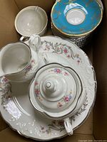 Box view showing sugar bowl, creamer, large floral plate, turquoise saucers stack
