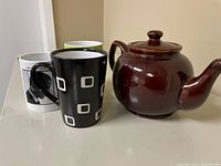 Teapot and three mugs side by side