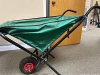 Side view showing entire wheelbarrow—frame, sling bed, wheel, handles
