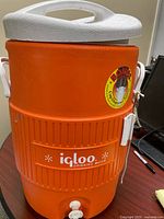 Full view of Igloo orange 5-gallon cooler with lid and handles