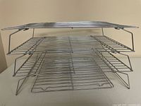 Side view showing three racks stacked with legs extended and one flat rack on top