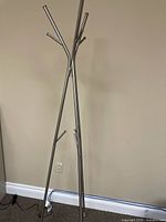 Full view of silver metal coat rack standing against wall