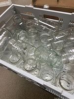 Crate containing numerous clear glass mason jars of varying sizes