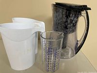 Front view of all four items: clear pitcher, measuring cup, two white containers