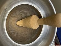 Interior view showing perforations and wooden pestle inserted