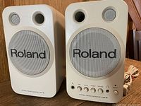 Front view of both Roland MA-8 speakers showing grills, ports and branding