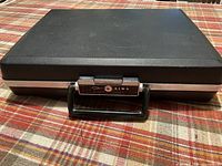 Closed black Aiwa hard case resting on table