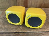 Front view of both yellow Sony cube speakers with grilles visible
