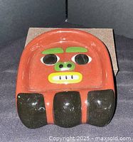 Front view of ashtray showing full totem face design and glazing