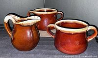 Front view of two soup bowls and pitcher showing brown drip glaze