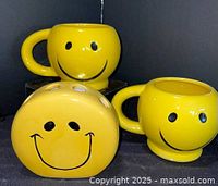 Front view of two mugs and holder showing smiley faces