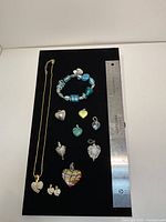 All jewelry items laid out on black display with ruler for scale