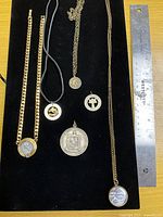 All six coin jewellery pieces laid out on black background