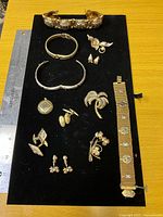 Full view of all jewellery items on black board with ruler for scale