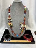 Full lot view showing necklace on bust with two cuffs and ruler for scale