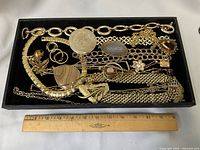 Overview of entire tray with all gold-tone jewellery and ruler for scale