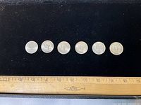 Six coins lined up beside ruler