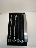 All four necklaces laid out with ruler for scale