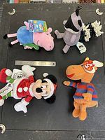 Group shot of all four plush toys with ruler for scale