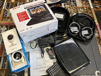 Group shot showing boxed DVD player, EZVIZ Mini O camera box, headphones in case, loose DVD player unit with accessories