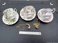 Front view of three teacup sets with necklaces and ruler for scale