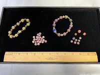 Overview of two bracelets and loose beads with ruler for scale