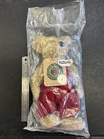 Full view of bear in sealed bag next to ruler for scale