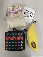 Overview of three travel games: Qwirkle case, Bananagrams pouch, Story Stones bag and card