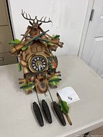 Full view of cuckoo clock with weights and pendulum on table