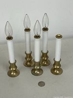 Five brass battery candles with a coin for scale