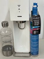 front view of SodaStream machine, bottle, and one cylinder