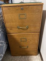 Front view of oak file cabinet showing two drawers, lock, brass-tone hardware