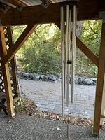 Full view of large aluminum tubular wind chime hanging from porch