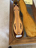 Wooden Appalachian dulcimer in open plush-lined hard case with booklet