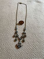 Full view of necklace and brooch on fabric background