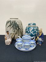 Group shot of all items: vase, cloisonné jar, tea set, mudmen