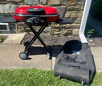 Grill on stand beside carrying case