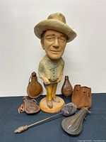 Front view of plaster cowboy statue and grouping of powder pouches and flask
