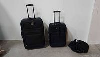 Two upright suitcases and small carry bag shown together for scale and completeness