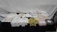 Group shot of all crocheted and embroidered doilies laid out on table