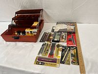 Overall lot layout: plastic case open with contents, packaged pens, cartridges, guide booklet, ruler for scale