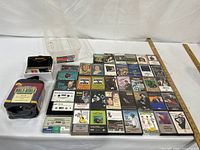 Group shot of radio, sealed Bible set, loose and cased tapes, storage bin