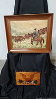 Both the framed cowboy painting and the wood inlay plaque displayed together