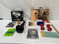 All items laid out including hair dryer, magnifier, dumbbells, massager, optical aids, gloves, pill box, gift bag