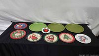 Overall view showing two green metal trays, eight plastic holiday plates and crocheted hot pad